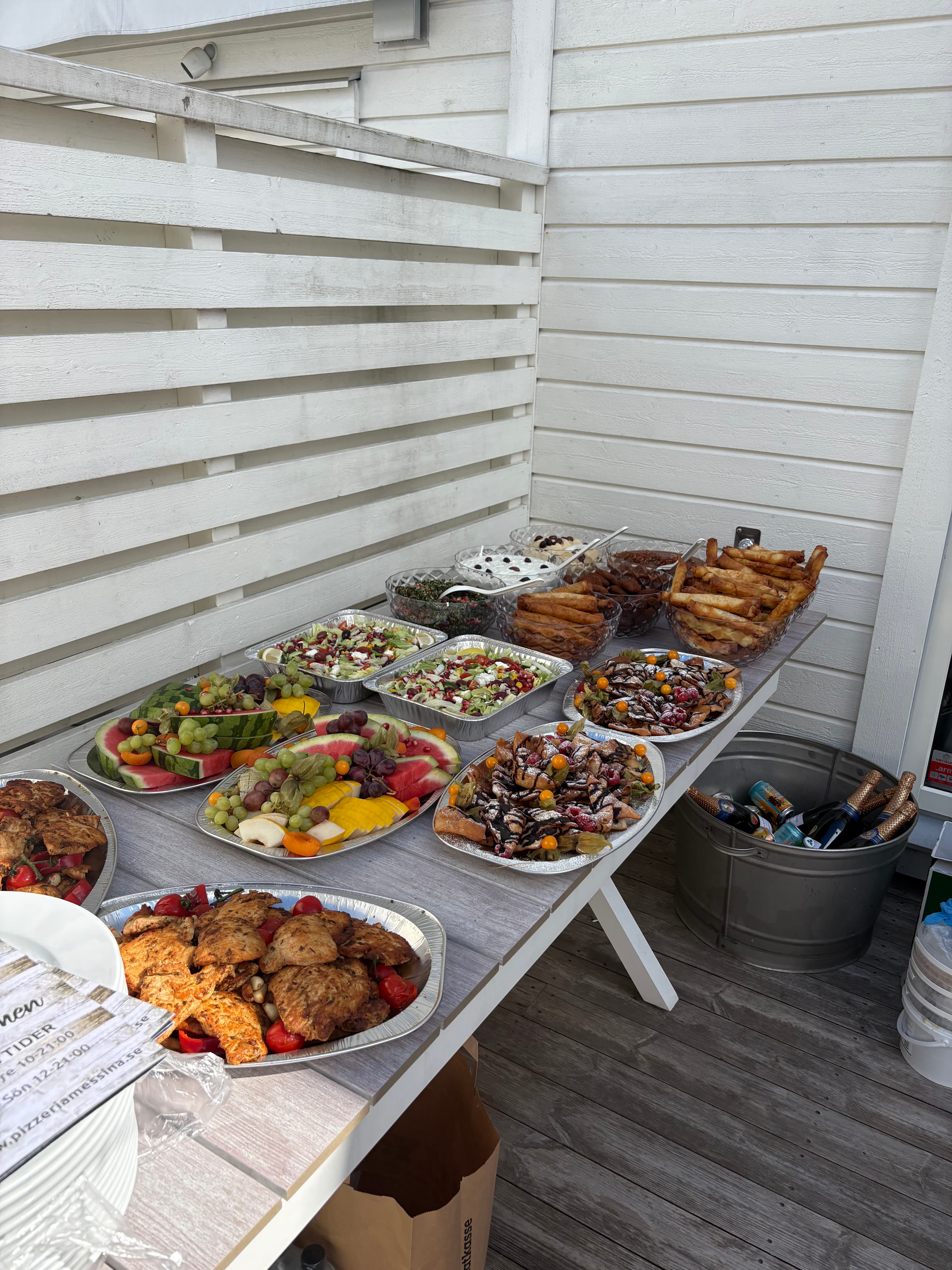 Långt cateringbord med mat, dryck i iskar och menyer från Pizzeria Messina