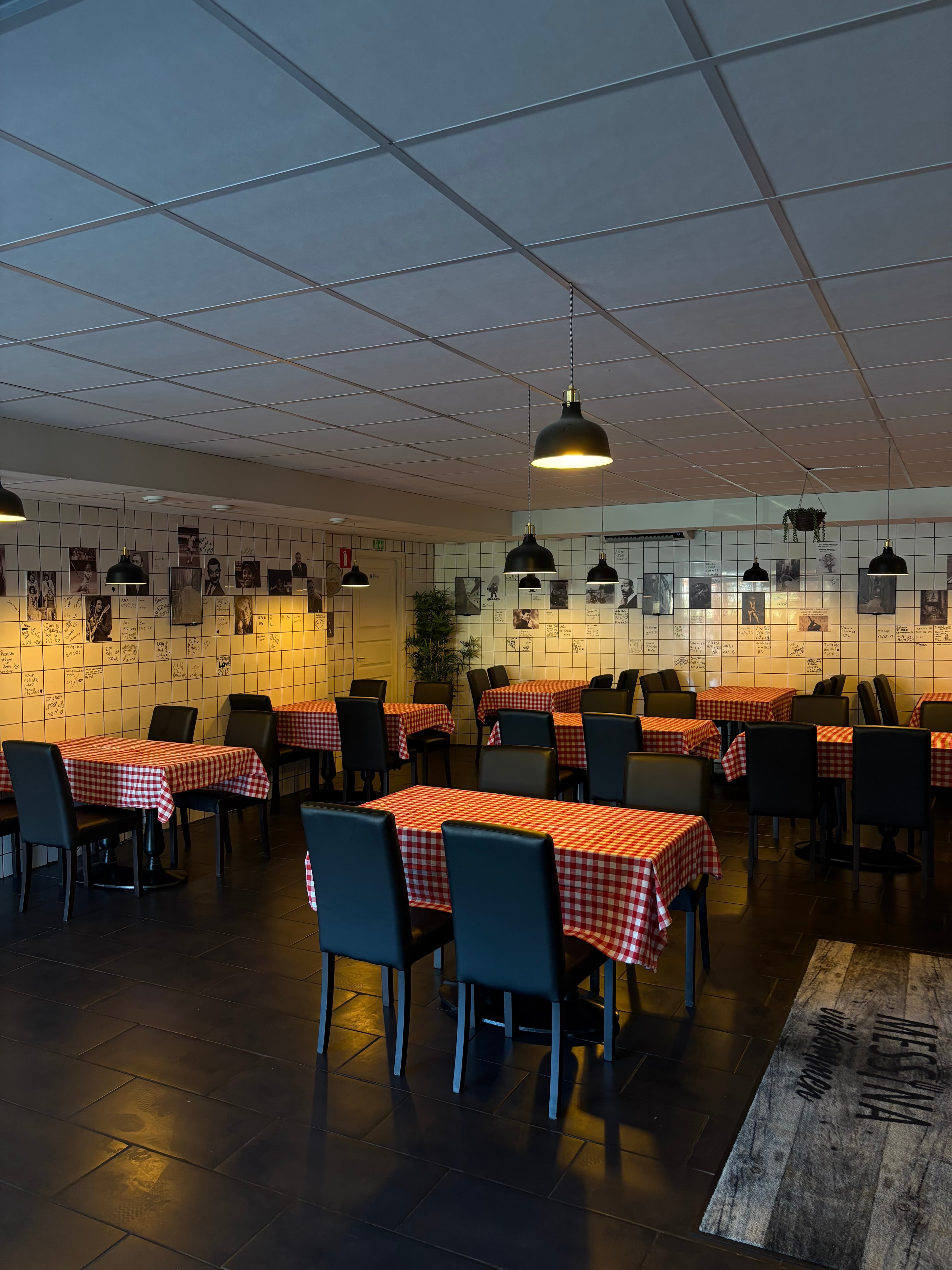 Restaurangens matsal med rödrutiga dukar, svarta stolar och hängande lampor